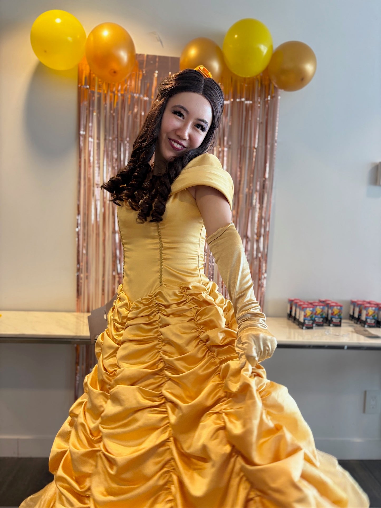 Woman in a yellow dress with balloons and a curtain in the background